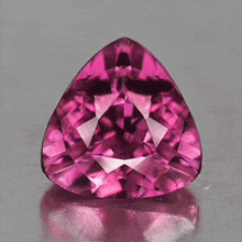 a pear shaped pink stone is sitting on a gray surface