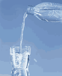 a bottle of water is being poured into a glass on a blue background