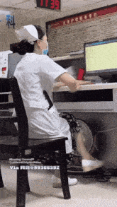 a nurse wearing a mask is sitting in a chair in front of a computer .