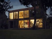 a large house with a lot of windows is lit up at night surrounded by trees .