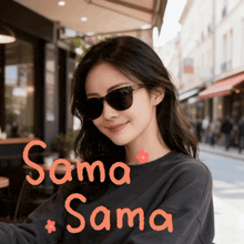 a woman wearing sunglasses and a black shirt with the name sama written in orange