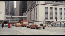 a row of cars are driving down a street in front of a building that says ' places ' on it