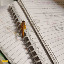 a dragonfly is sitting on top of a spiral notebook with the words realme shot by sagar on the bottom