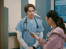 a man in scrubs talks to a woman in front of a sign that says ' are you afraid to move '