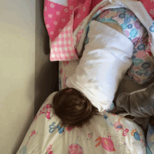 a child is laying on a bed with a blanket that has birds and butterflies on it