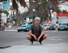 a young man squatting down in front of a sign that says ' a ' on it