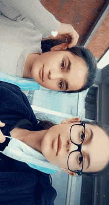 two girls wearing face masks and glasses pose for a photo