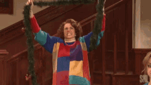 a woman in a colorful sweater is holding a christmas wreath in her hands