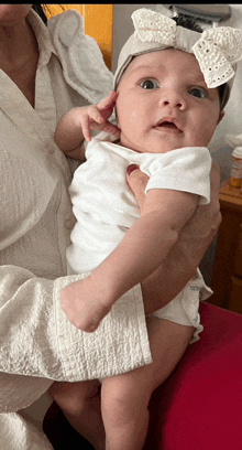 a woman is holding a baby in her arms and the baby is wearing a white headband