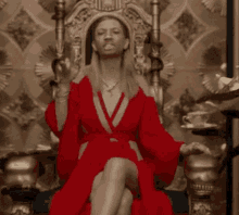 a woman in a red robe is sitting on a throne