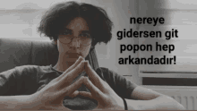 a man wearing glasses sits in a chair with the words nereye gidersen git popon hep arkandadir