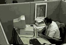 a man is sitting at a desk in front of a computer monitor .