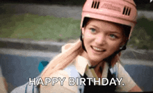 a young girl wearing a pink helmet is smiling and saying happy birthday .