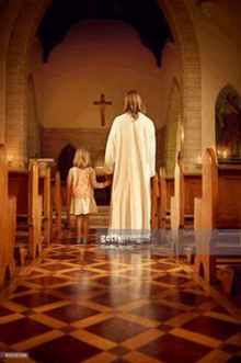 jesus is walking down the aisle of a church with a little girl .