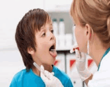 a doctor is examining the throat of a young boy .