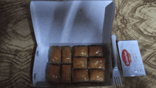 a box of baklava next to a fork and a packet of sekerler