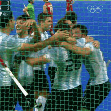 a group of hockey players hugging behind a net with a scoreboard in the background that says 2 3 4th