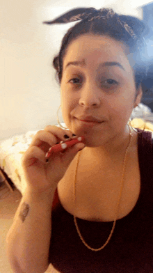 a woman with a tattoo on her wrist is smoking a red cigarette