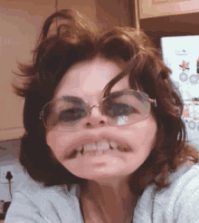 a woman wearing glasses making a funny face in front of a refrigerator