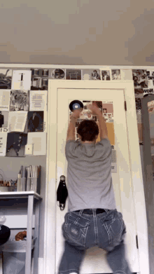 a man is holding a record in front of a door with a poster on the wall that says ' i '