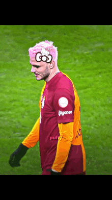 a soccer player with pink hair has a hello kitty drawing on his head .