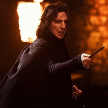 a man in a black coat is holding a wand in his right hand