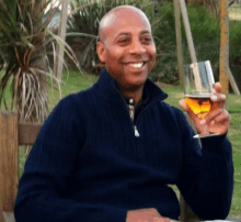 a man in a blue sweater holds a glass of beer