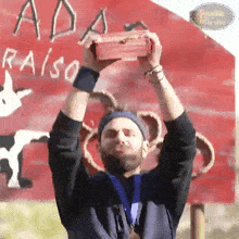 a man with a medal around his neck is holding a box in front of a sign that says paradiso