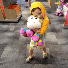 a young boy holding a stuffed monkey in a toy store