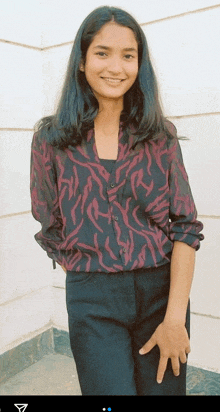 a woman wearing a zebra print shirt and black pants is smiling