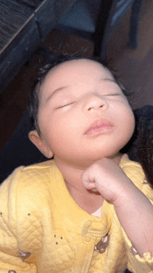 a baby in a yellow jacket with a bear on it is sleeping