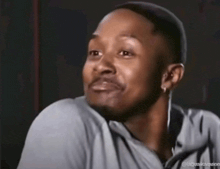 a man in a gray shirt is making a funny face