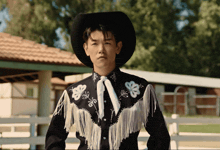 a man wearing a cowboy hat and fringed shirt