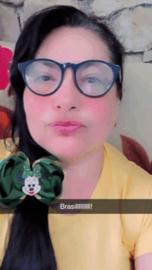 a woman wearing glasses and a green bow with the word brasil on the bottom