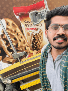 a man wearing glasses is standing in front of a bag of ice cream that says ' oiomja ' on it