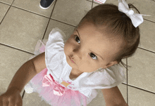 a little girl wearing a white top and pink tutu