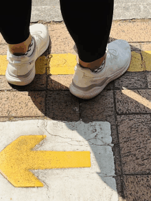 a person standing on a sidewalk with a yellow arrow pointing to the right