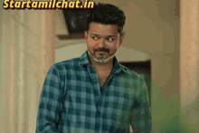 a man in a blue plaid shirt is standing in front of a wall with the words starttamilchat.in above him