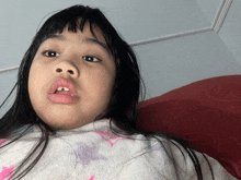 a young girl with a missing tooth looks at the camera with her mouth open