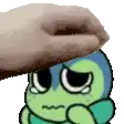 a hand is putting a donut on top of a cartoon character 's head .