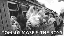 a black and white photo of a train with trolls looking out of the windows .