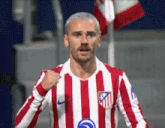 a soccer player wearing a red and white striped jersey with the letters atm on the front
