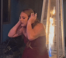 a woman in a red dress is wearing headphones while standing in front of a heater .