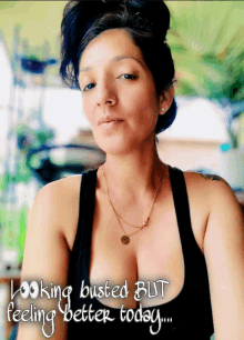 a woman in a black tank top with the words " looking busted but feeling better today "