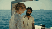 a man and a woman are standing on a boat with the word paused on the side