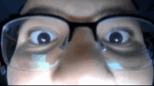 a close up of a person wearing glasses with their eyes wide open