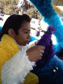 a little girl is sitting next to a stuffed animal with a purple hat on it