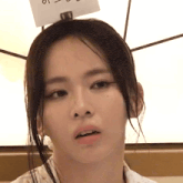 a close up of a woman 's face with a sign on her head that says ' i 'm sorry '