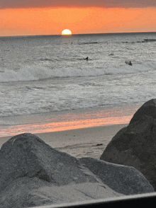 a sunset over the ocean with a surfer in the distance