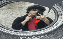 a man taking a picture of himself in a mirror with a red heart in the corner